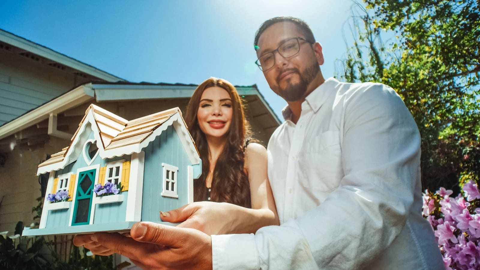 Couple recevant les clés lors d'un achat immobilier devant une maison